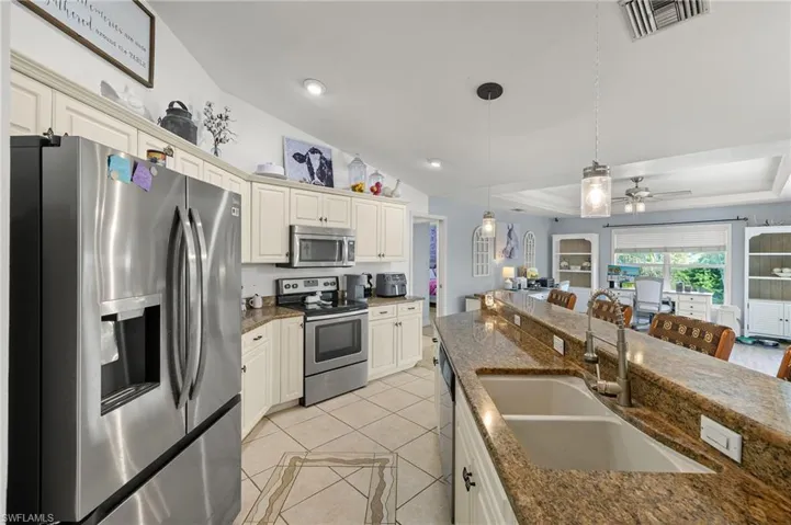 Kitchen featuring visible vents, a sink, appliances with stainless steel finishes, light tile patterned floors, and hanging light fixtures