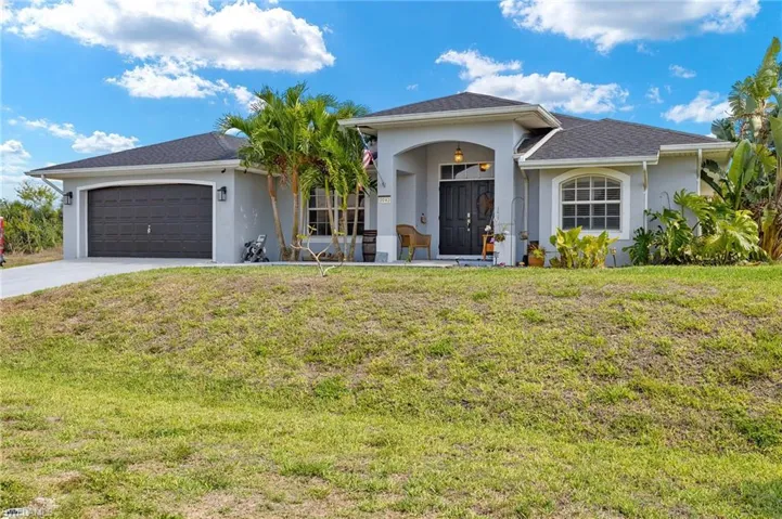 View of front facade with concrete driveway, stucco siding, an attached garage, and a front yard