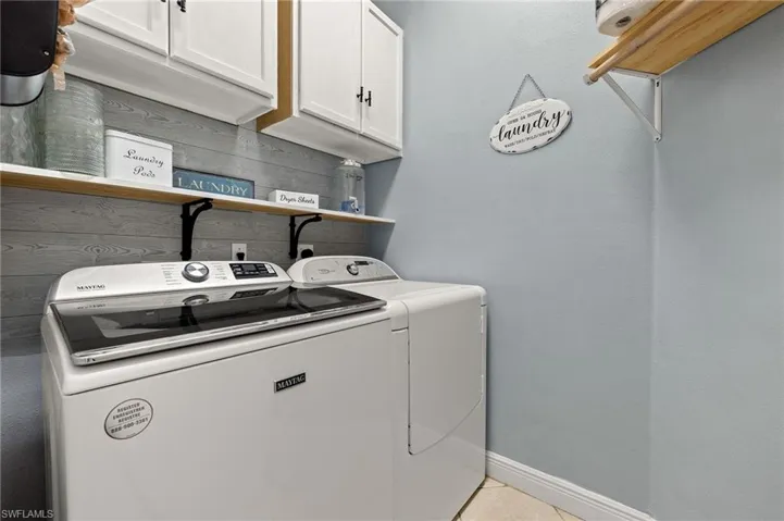 Laundry area with baseboards, tile patterned flooring, washing machine and dryer, and cabinet space