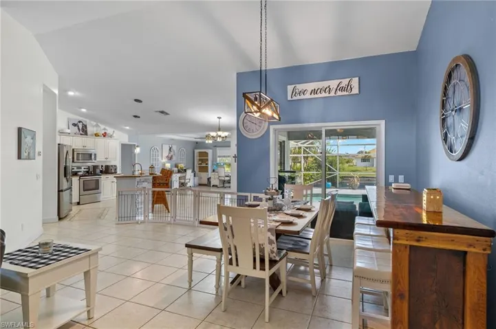 Dining space featuring light tile patterned flooring, a chandelier, and lofted ceiling