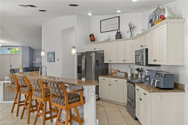 Kitchen with visible vents, appliances with stainless steel finishes, light tile patterned floors, lofted ceiling, and a breakfast bar