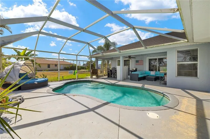 Pool featuring glass enclosure, an outdoor living space, a ceiling fan, and a patio area