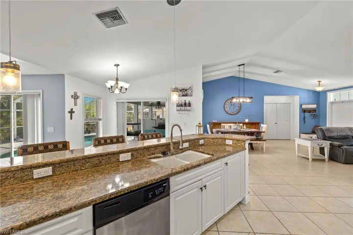 Kitchen with a sink, dishwasher, a chandelier, vaulted ceiling, and visible vents