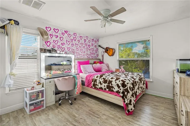 Bedroom with visible vents, light wood-style flooring, ceiling fan, and baseboards