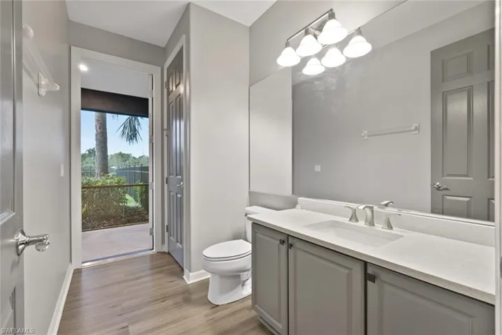 Bathroom with toilet, wood finished floors, vanity, and baseboards