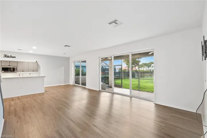 Unfurnished living room featuring wood finished floors, baseboards, recessed lighting, and a sink