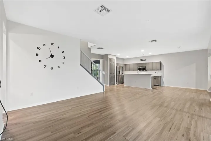Unfurnished living room with stairway, light wood-style flooring, recessed lighting, and baseboards