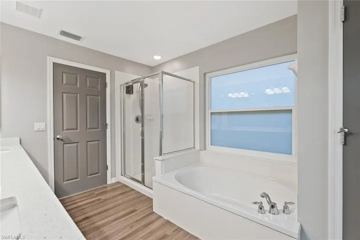 Full bathroom featuring a stall shower, vanity, a bath, and wood finished floors