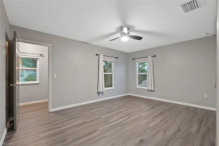 Unfurnished room with ceiling fan, wood finished floors, and baseboards