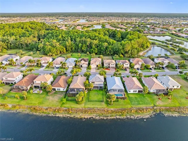 Aerial view of property and surrounding area with a nearby body of water and nearby suburban area