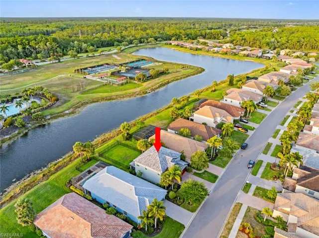 Aerial perspective of suburban area with a nearby body of water and a heavily wooded area