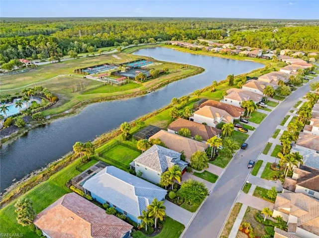 Aerial perspective of suburban area featuring a nearby body of water and a heavily wooded area