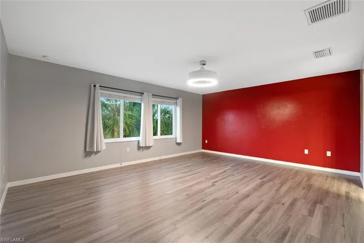 Empty room featuring wood finished floors, baseboards, and an accent wall