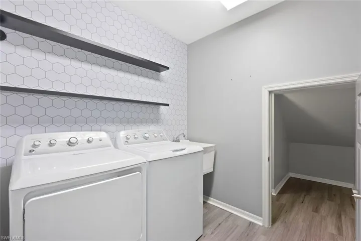 Laundry room featuring washer and dryer, light wood-type flooring, and baseboards