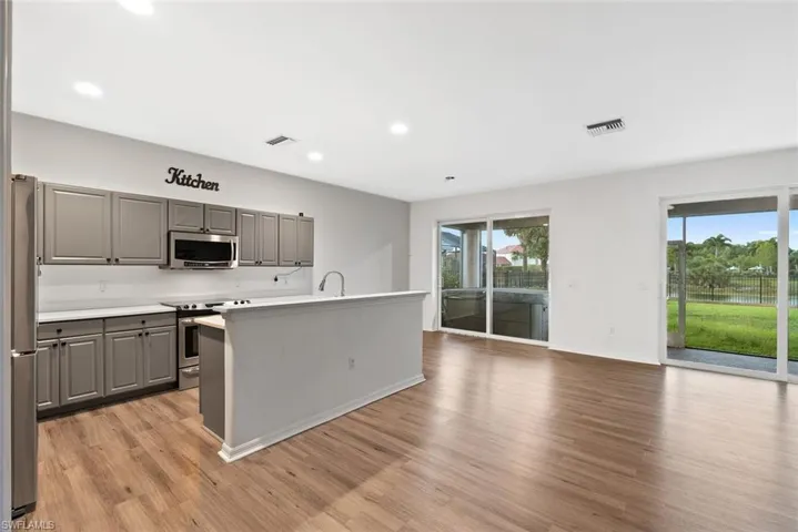 Kitchen featuring stainless steel appliances, gray cabinetry, plenty of natural light, light wood finished floors, and recessed lighting