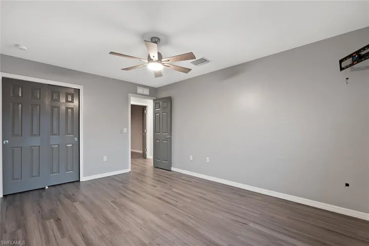 Unfurnished bedroom with wood finished floors, baseboards, and a ceiling fan