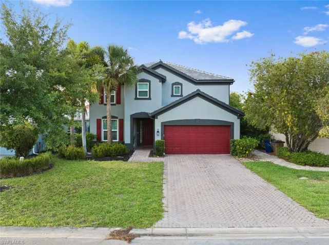 Traditional-style home with decorative driveway, a front lawn, stucco siding, and a garage