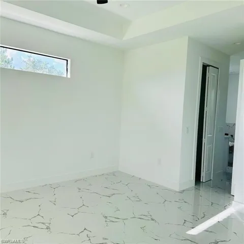 Spacious room featuring white walls, patterned tile flooring, and a tray ceiling with recessed lighting