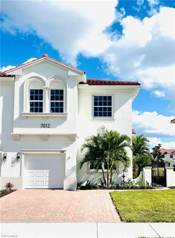 Mediterranean / spanish house featuring an attached garage, stucco siding, a gate, a tile roof, and decorative driveway
