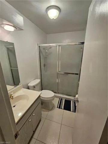 Full bath featuring vanity, a stall shower, and light tile patterned floors