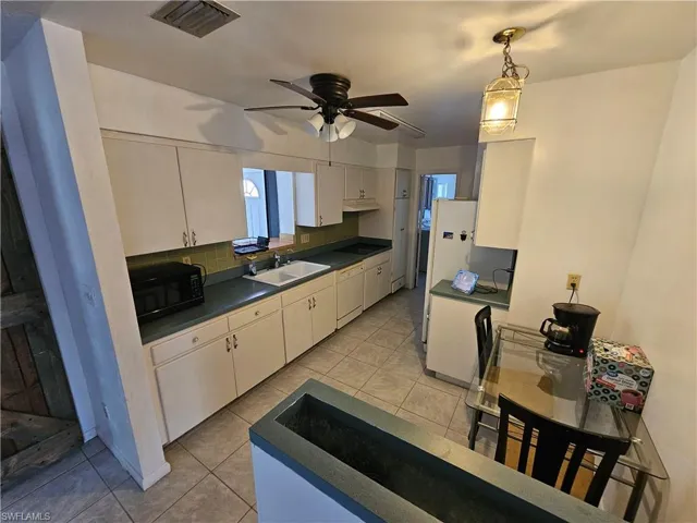 Kitchen featuring dark countertops, black appliances, backsplash, and light tile patterned floors