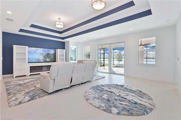 Living area with a glass covered fireplace, crown molding, and a tray ceiling