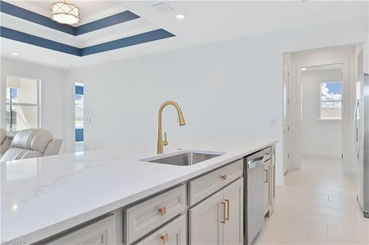 Kitchen featuring light stone countertops, appliances with stainless steel finishes, recessed lighting, a tray ceiling, and open floor plan