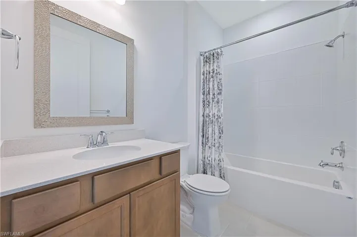 Bathroom featuring vanity, shower / bath combination with curtain, and light tile patterned floors