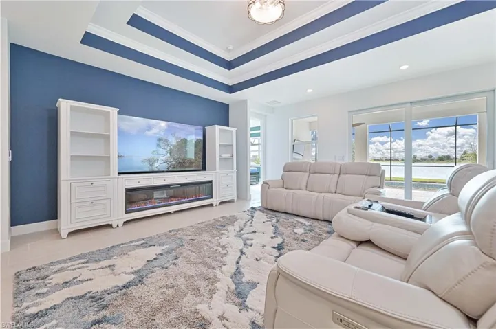 Living area featuring healthy amount of natural light, ornamental molding, and a tray ceiling