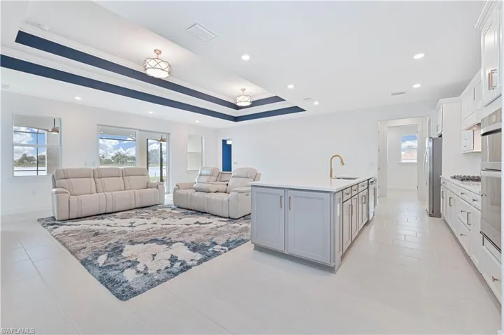 Living area with healthy amount of natural light, a tray ceiling, recessed lighting, and ornamental molding