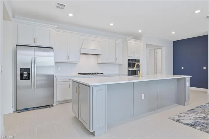 Kitchen with appliances with stainless steel finishes, white cabinets, premium range hood, gray cabinets, and recessed lighting