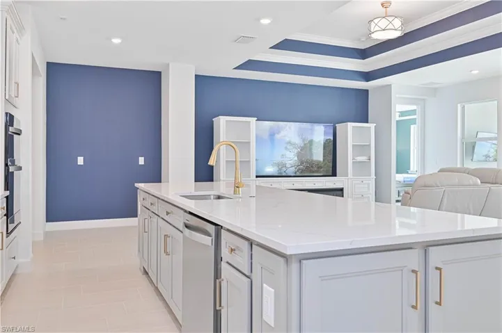 Kitchen featuring light stone counters, open floor plan, white cabinetry, a kitchen island with sink, and recessed lighting