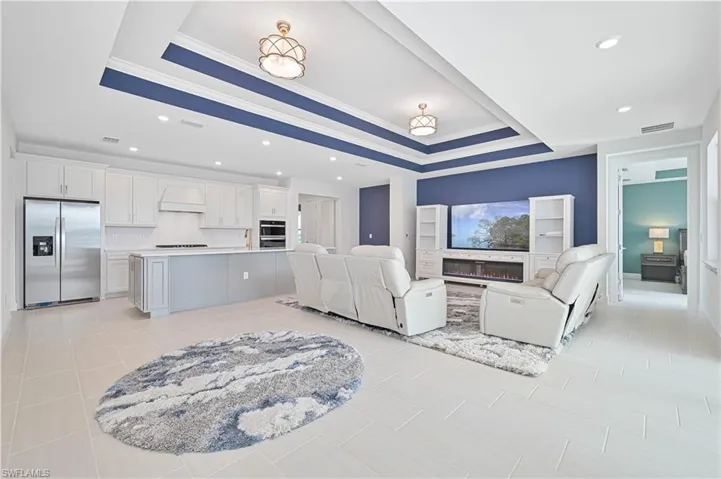 Living room featuring a glass covered fireplace, recessed lighting, ornamental molding, and a raised ceiling