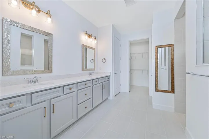 Full bathroom with double vanity, a spacious closet, and light tile patterned flooring