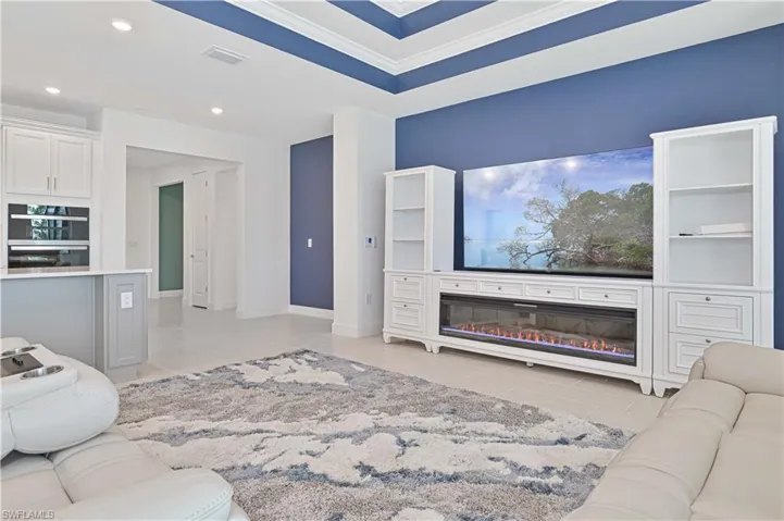 Living area with a glass covered fireplace, a tray ceiling, and recessed lighting