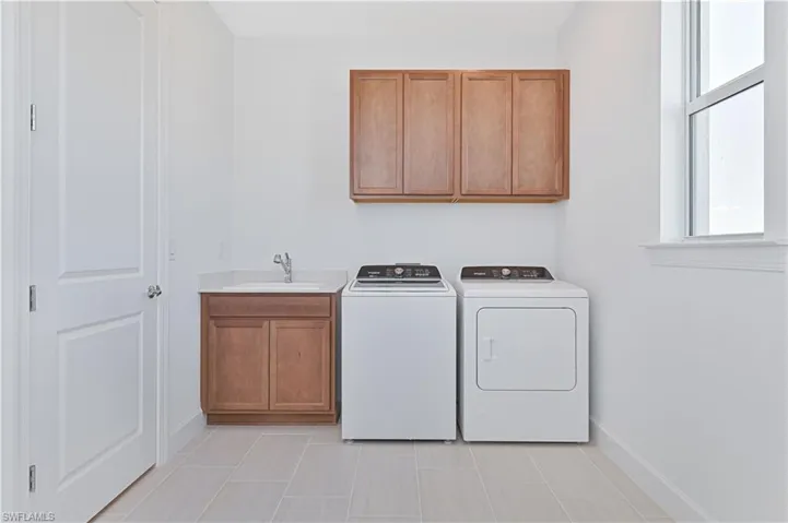 Washroom featuring plenty of natural light, cabinet space, and independent washer and dryer