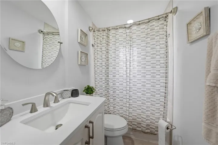 Full bathroom with curtained shower and vanity