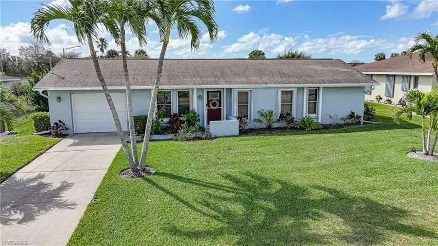 Ranch-style house featuring stucco siding, a front lawn, an attached garage, concrete driveway, and a shingled roof