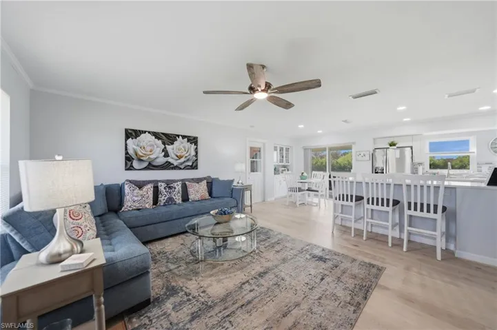 Living area featuring ceiling fan, light wood finished floors, crown molding, and recessed lighting