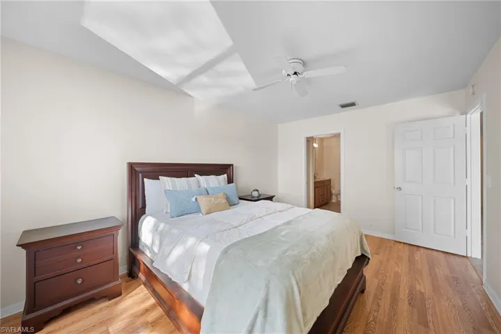 Bedroom with light wood-type flooring, ceiling fan, and ensuite bathroom