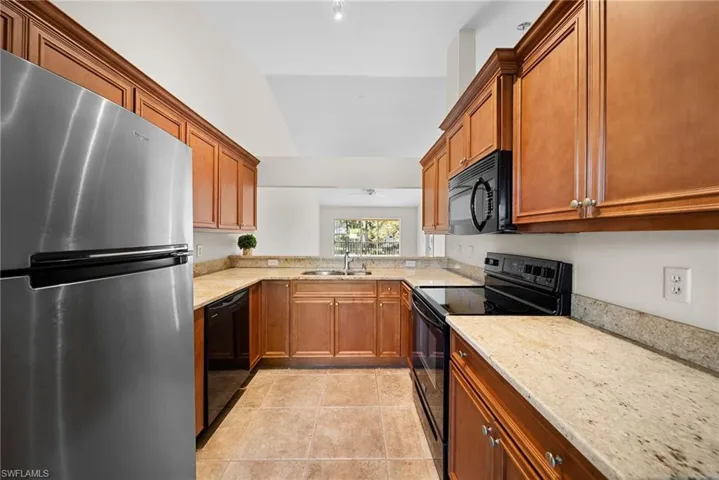 Kitchen featuring black appliances, brown cabinets, light stone countertops, light tile patterned floors, and ceiling fan