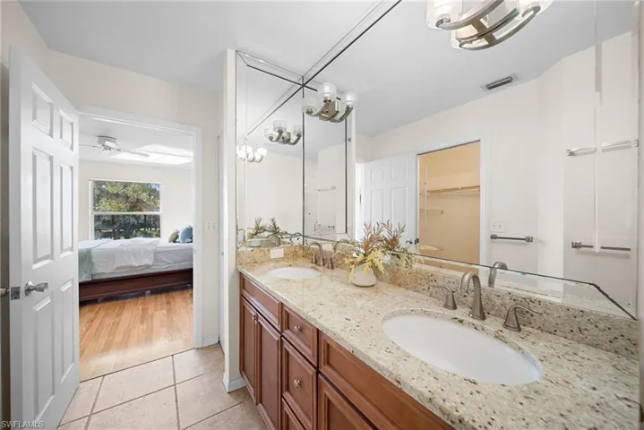 Full bathroom featuring double vanity, ensuite bath, a spacious closet, light tile patterned flooring, and a chandelier