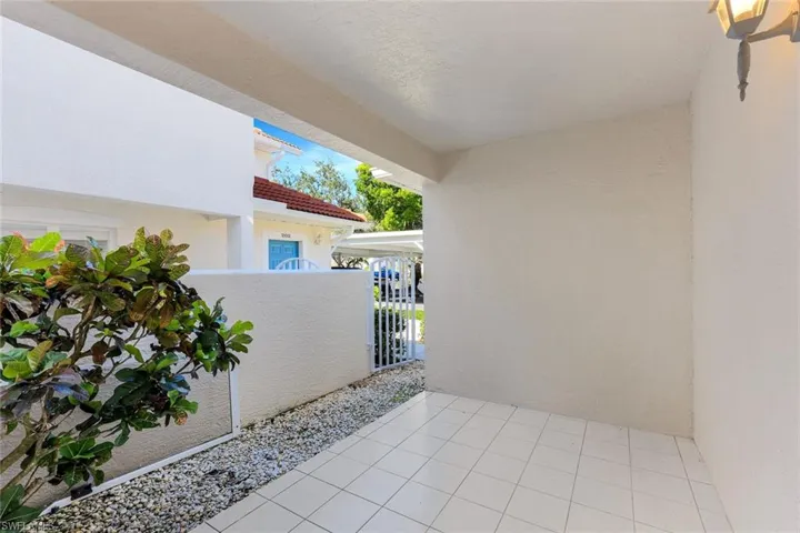 Covered patio featuring ceramic tile flooring, a textured stucco wall finish, and an exterior wall-mounted light fixture