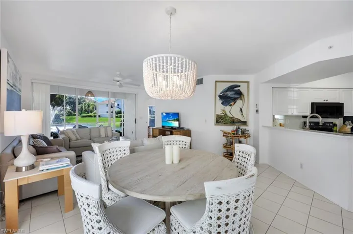 Open-concept area featuring tile flooring, a multi-light beaded chandelier, and sliding glass doors