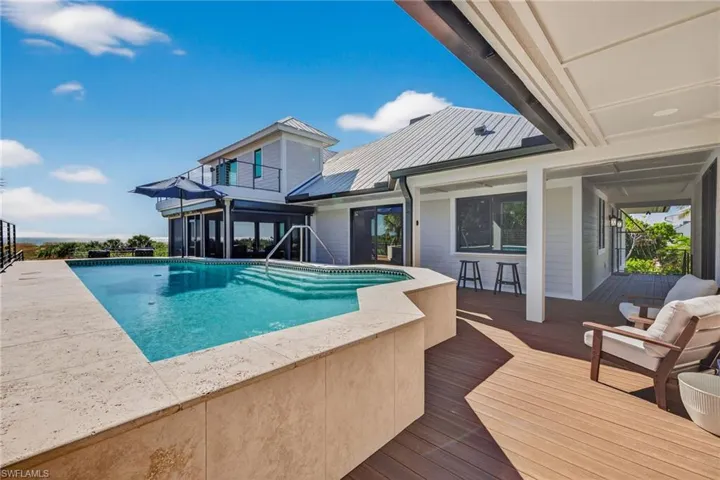 Outdoor pool with a patio, a wooden deck, and a balcony