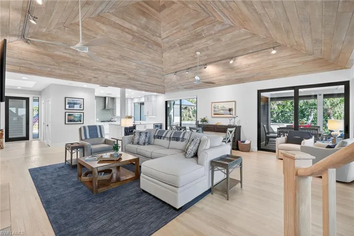 Living room featuring track lighting, light wood-style floors, ceiling fan, and wood ceiling