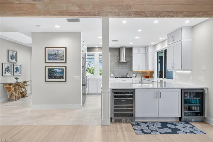 Bar featuring wine cooler, white cabinetry, recessed lighting, light wood finished floors, and light stone counters