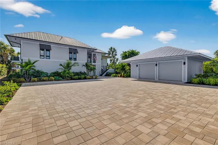 View of front facade with a garage, a metal roof, decorative driveway, and an outdoor structure
