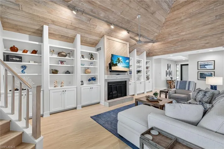 Living area featuring rail lighting, a tile fireplace, light wood-type flooring, stairs, and wooden ceiling