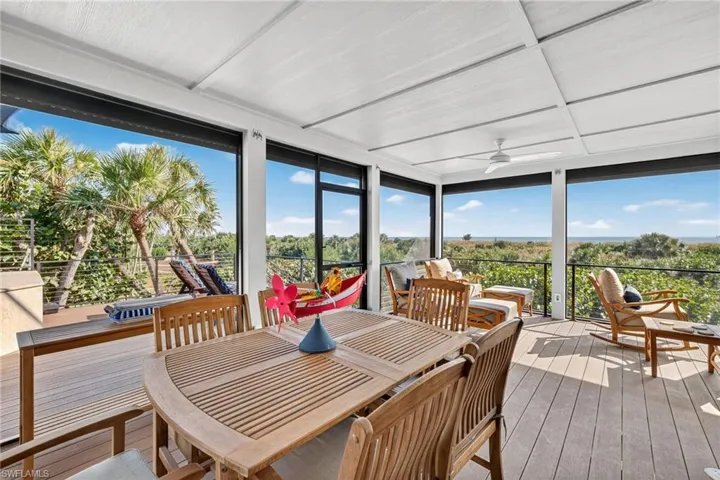 Sunroom / solarium with ceiling fan, outdoor dining space, hardwood / wood-style flooring, a deck, and a wall of windows